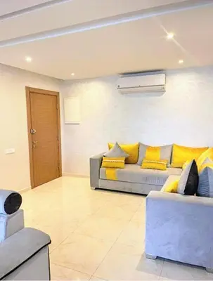 a living room with a couch and yellow pillows at Un élégant appartement à louer à Marrakech avec deux piscines et une situation en centre ville in Marrakech