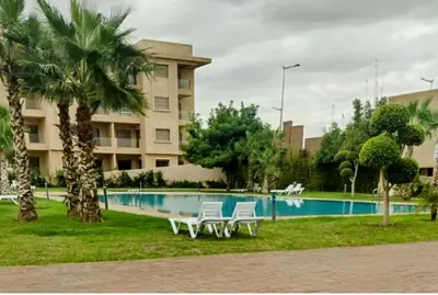 a resort with a pool and palm trees and a building at Un élégant appartement à louer à Marrakech avec deux piscines et une situation en centre ville in Marrakech