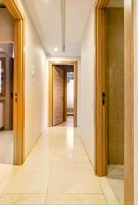 an empty hallway with wooden doors and tile floors at Un élégant appartement à louer à Marrakech avec deux piscines et une situation en centre ville in Marrakech