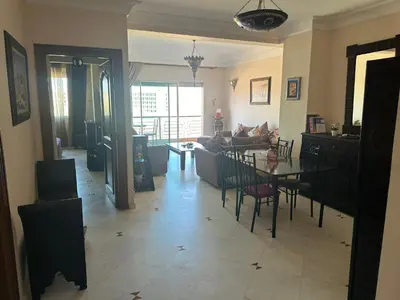 a living room with a table and a couch at Magnifique appartement 2 chambres et piscine de standing in Marrakech