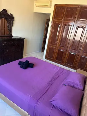 a large purple bed in a room with wooden cabinets at Magnifique appartement 2 chambres et piscine de standing in Marrakech