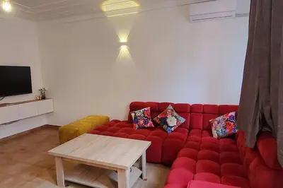 a red couch in a living room with a table at Appartement bien équipé à louer in Marrakech