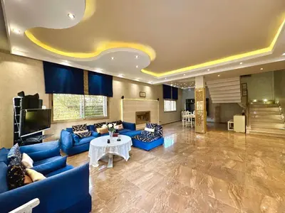 a large living room with blue couches and a tv at Villa des Ocres - Élégance et Luxe à 15 min du centre ! in Marrakech