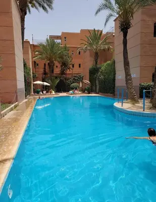 a large blue swimming pool with palm trees and a building at M-S Riad in Marrakech