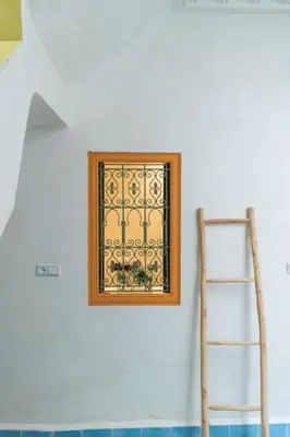 a ladder and a picture on a white wall with a window at Riad Pistache 135m2 in der Medina mit Terrasse in Marrakech