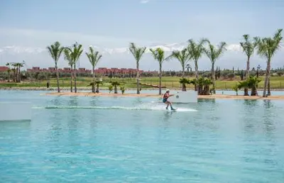 a man water skiing on a body of water with palm trees at VILLA Atlas in Sraghna