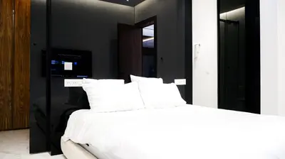 a bedroom with a bed with white sheets and a mirror at VILLA Atlas in Sraghna
