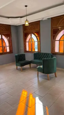 a living room with two green couches and windows at Villa riad al salam in Marrakech