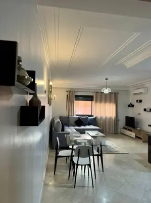 a living room with a couch and a table and chairs at Cosy Appartement Famille in Marrakech