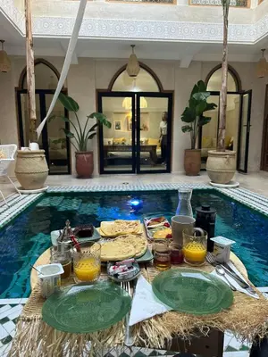 a table with food and drinks in front of a swimming pool at Riad Eden Dorient in Marrakech