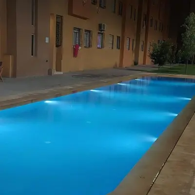 a pool of blue water in front of a building at Très belle expérience ! in Marrakech