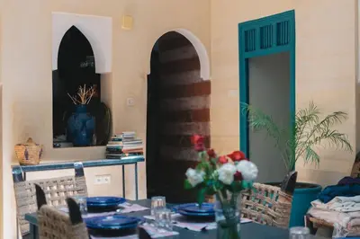 a dining room with a table with blue plates and flowers at Riad Bouhalla 240m2 in der Medina mit Terrasse in Marrakech