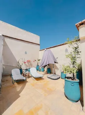 an outdoor patio with two chairs and an umbrella at Riad Bouhalla 240m2 in der Medina mit Terrasse in Marrakech