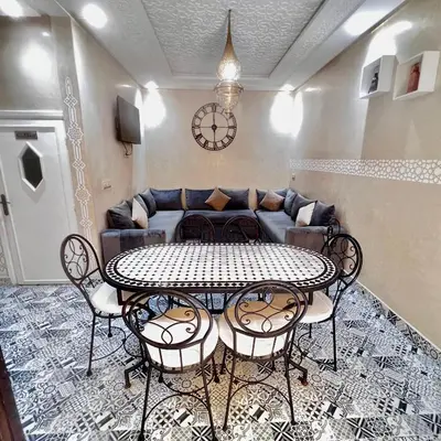 a table and chairs in a living room with a couch at Cozy Apartment Near Airport Terminal Modern Apartment Close to Airport in Marrakech