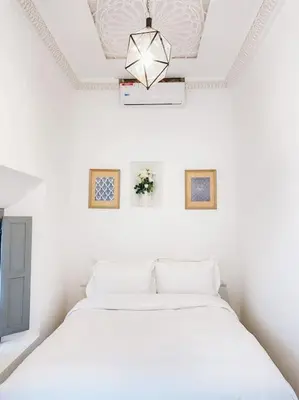 a white bedroom with a bed and a chandelier at Riad Dar Cidi 100m2 in der Medina mit Terrasse in Marrakech