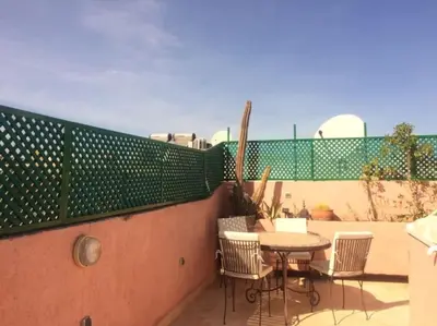 a patio with a table and chairs on a balcony at Riad Petit Palais 100m2 in der Medina mit Terrasse in Marrakech
