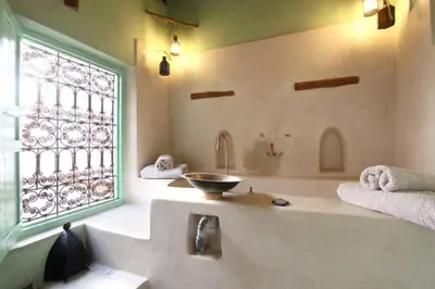 a bathroom with a tub with a sink and a window at Riad Petit Palais 100m2 in der Medina mit Terrasse in Marrakech