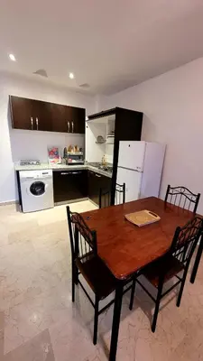 a kitchen with a wooden table and chairs and a kitchen with a refrigerator at appartement 29 entier avec balcon in Marrakech