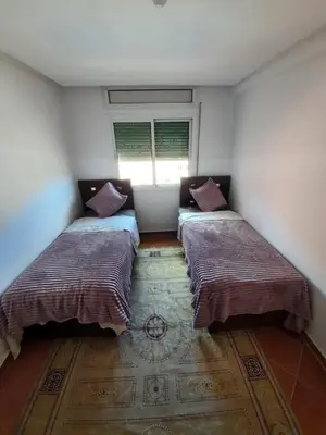 two beds in a small room with a window at La Paix Appart in Marrakech