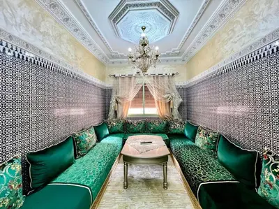 a dining room with green furniture and a chandelier at appart Confortable BASSATIN GUILIZ in Marrakech