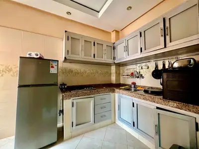 a kitchen with white cabinets and a green refrigerator at appart Confortable BASSATIN GUILIZ in Marrakech
