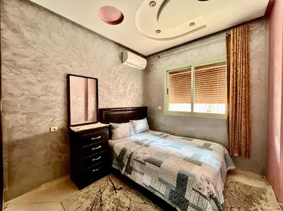a bedroom with a bed with a dresser and a window at appart Confortable BASSATIN GUILIZ in Marrakech