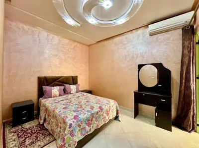 a bedroom with a bed and a dresser and a mirror at appart Confortable BASSATIN GUILIZ in Marrakech