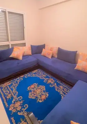 a blue couch in a living room with a rug at Excellent apparentement, in Marrakech