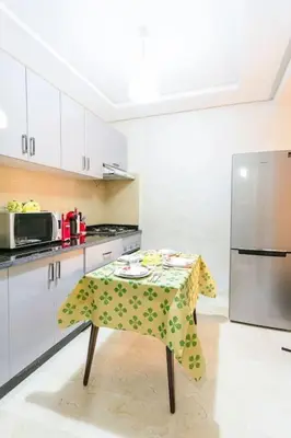 a kitchen with a table and a refrigerator at Guéliz Cosy apart 2 Bedrooms in Marrakech