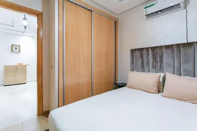 a bedroom with a white bed and a wooden closet at Guéliz Cosy apart 2 Bedrooms in Marrakech