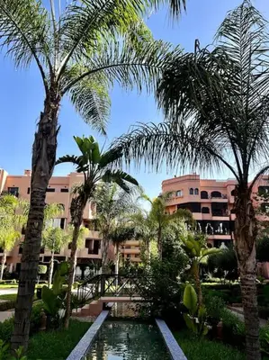 a resort with a pool and palm trees and a building at Resort med 24t sikkerhet og basseng - nærme Gueliz in Marrakech