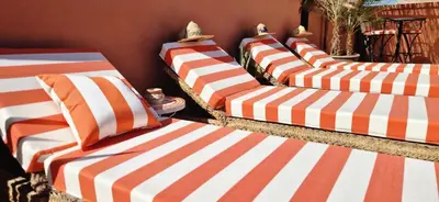 a group of beds with orange and white striped pillows at Riad Babmoon - Private Riad with Pool & Rooftop in Marrakech