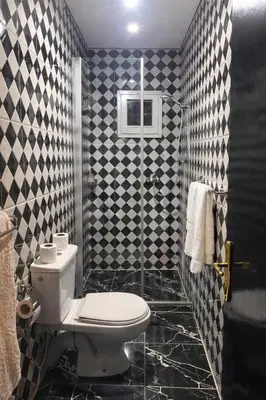 a bathroom with a toilet and black and white tiles at appartement au cœur du Madina in Marrakech
