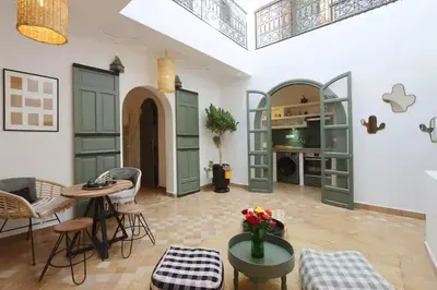 a living room with green doors and a table and chairs at Riad Ptit Kech, Bassin terrasse - Petits déjeuners in Marrakech