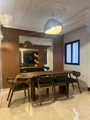 a dining room with a wooden table and green chairs at Appartement Neuf Carré EDEN in Marrakech