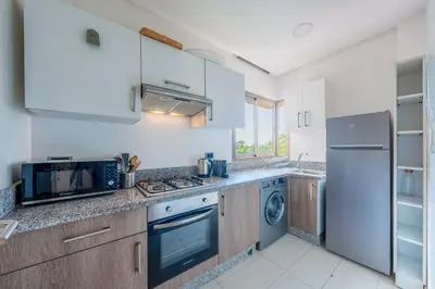 a kitchen with white cabinets and a stainless steel refrigerator at stylish appart with 3Bedrooms in Prestigia in Marrakech