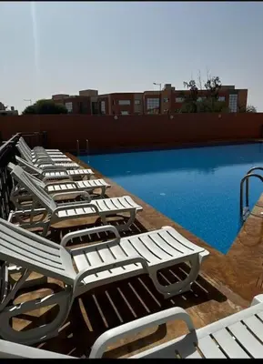 a row of lounge chairs next to a swimming pool at Magnifique appartement luxueux à 10mn du centre in Marrakech