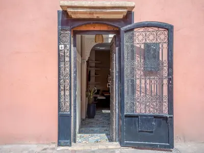 an entrance to a pink building with an open door at Riad Dar makhzne-location exclusive du Riad entier 4 chambres & terrasse in Marrakech