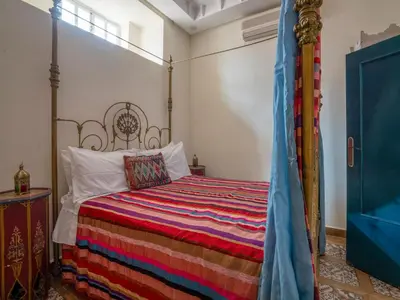 a bedroom with a bed with a colorful striped blanket at Riad Dar makhzne-location exclusive du Riad entier 4 chambres & terrasse in Marrakech