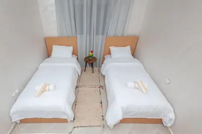 two twin beds in a small room with a table at New elegant apartment with 2 bedroom in Marrakech