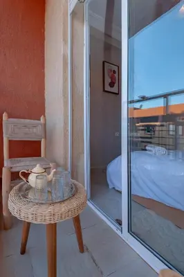 a rattan table with a glass door leading to a bedroom at New elegant apartment with 2 bedroom in Marrakech