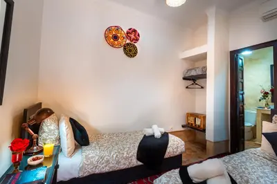 a bedroom with two beds and a clock on the wall at Riad Dar Haris in Marrakech