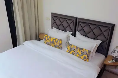 a bed with white sheets and yellow pillows at Appartement familial de luxe in Marrakech