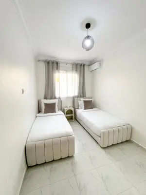 two beds in a room with white walls at Lyana Home in Marrakech