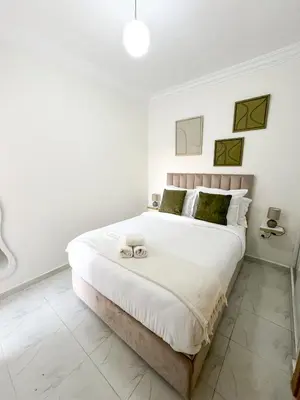 a white bedroom with a large bed with two towels on it at Lyana Home in Marrakech