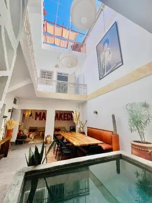 a living room with a table and a swimming pool at Votre riad privé en médina avec services inclus in Marrakech