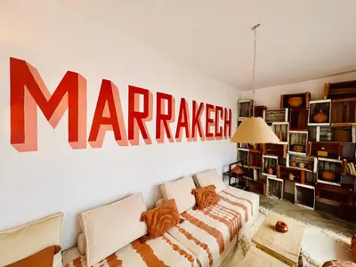 a living room with a marauder sign on the wall at Votre riad privé en médina avec services inclus in Marrakech