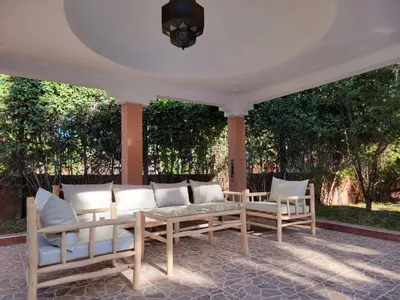 a porch with a couch and two chairs on it at Villa Camélia des 3 Z in Marrakech