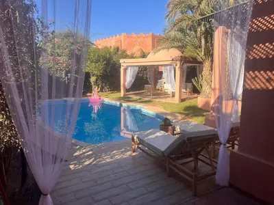 a swimming pool with a table and a chair next to it at Villa Camélia des 3 Z in Marrakech