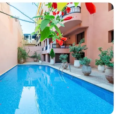a swimming pool in front of a building at Appart cosy centre-ville piscine et terrasse in Marrakech